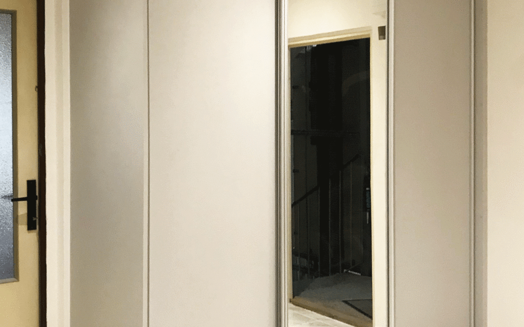 Vestavěná skříň s posuvnými dveřmi se zrcadlem ve světle šedivé barvě.