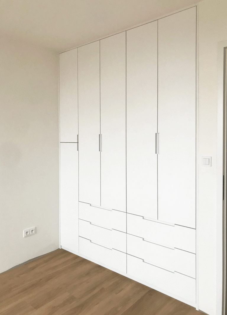 Vestavěná skříň s pantovými dveřmi a šuplíky a zafrézovanými úchytkami.