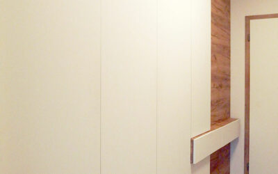 Vestavěná skříň do chodby s pantovými dveřmi v bílé barvě kombinované s dřevěnými dveřmi.