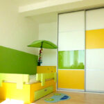 Dětský pokoj s postelí a vetsavěnou skříní s posuvnými dveřmi.