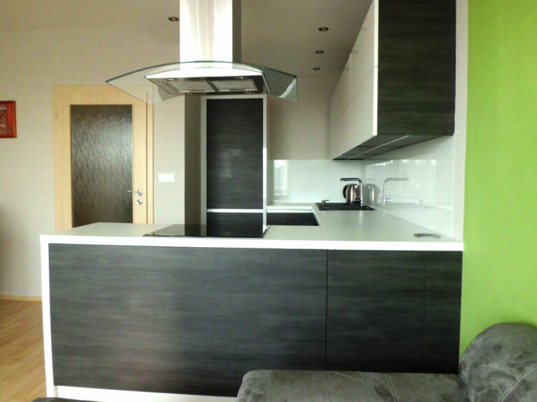 Kuchyň na míru do "U" v bílé barvě a tmavém dřevěném dekoru.