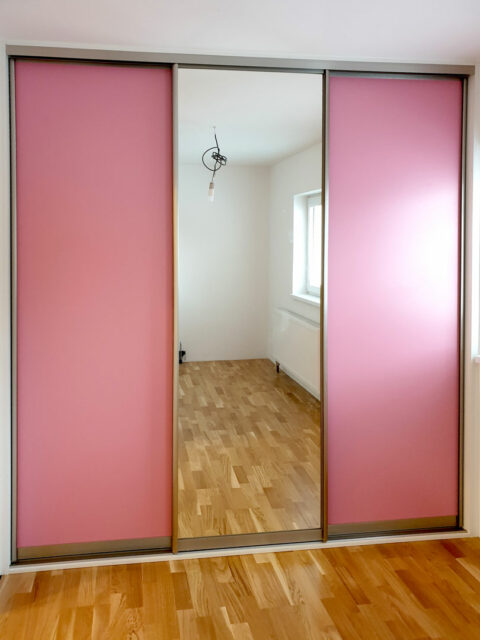 Skříň na míru s posuvnými dveřmi v růžové barvě se zrcadlem.