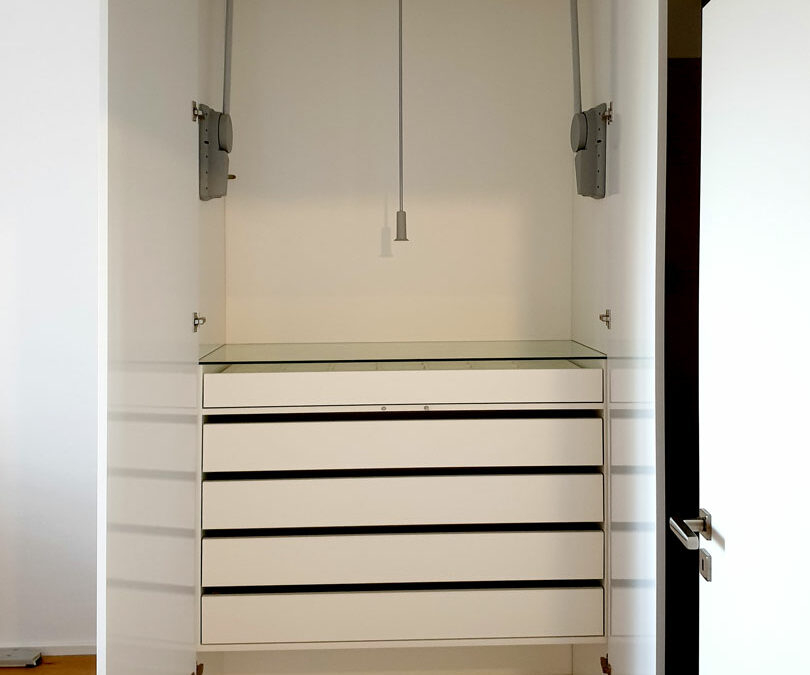 Otevřený pantový skříň se šuplíky a sklopnou šatní tyčí.