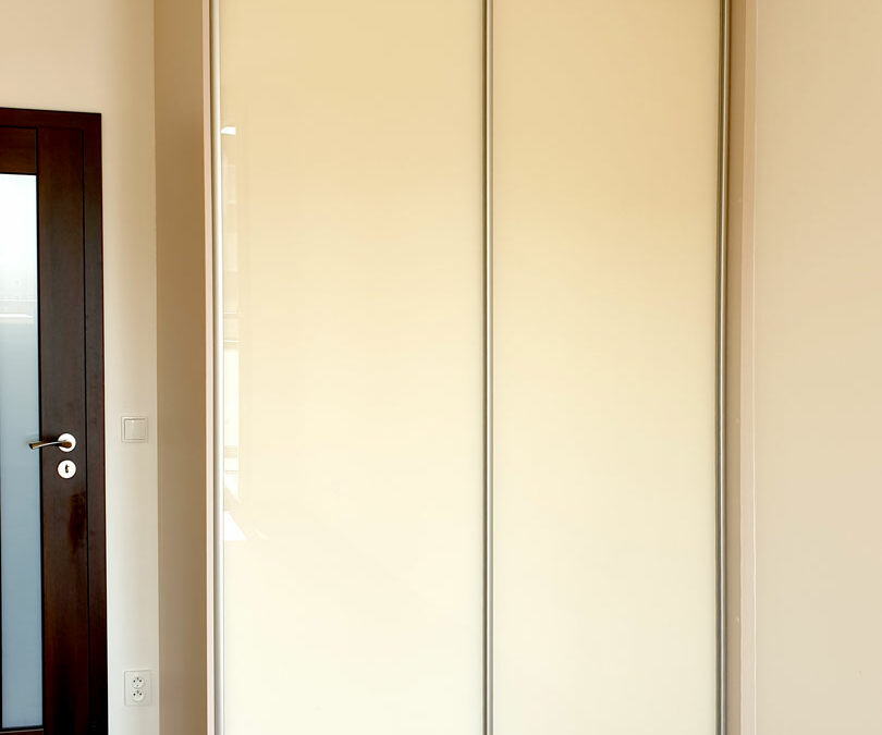 Vestavěná skříň na míru s posuvnými dveřmi v krémové barvě.