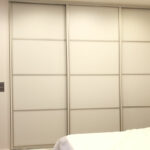 Realizace skříně na míru s posuvnými dveřmi v bílé barvě s horizontálním dělením dveří.