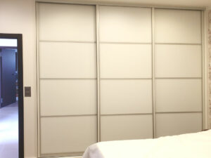 Realizace skříně na míru s posuvnými dveřmi v bílé barvě s horizontálním dělením dveří.