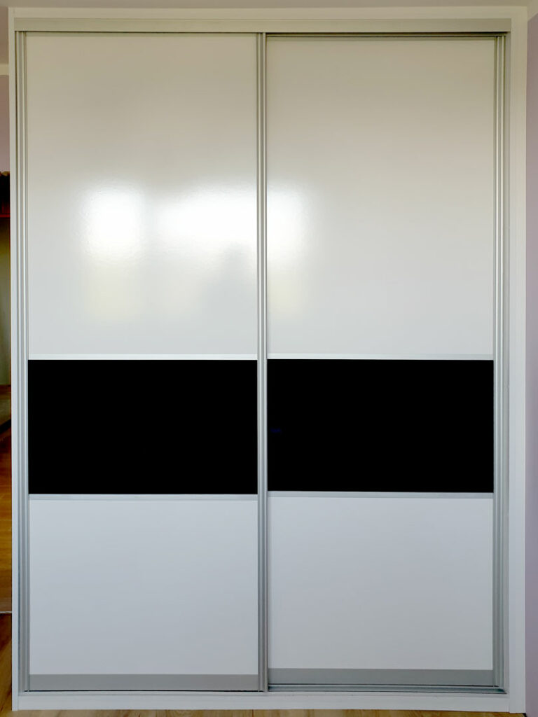 Vestavěná skříň s posuvnými dveřmi v bílé barvě s dělením černým pruhem.