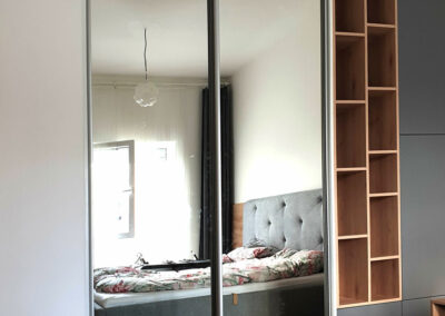 Realizace šatny na míru do ložnice s kombinací posuvných dveř, pantových dveří a dřevěné otevřené části.