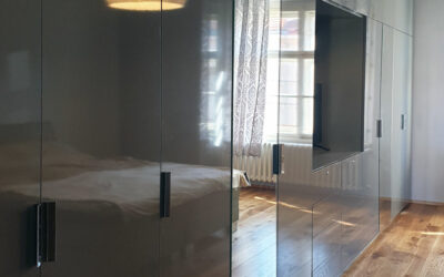 vestavene-skrine-realizace-095 Velké pantová skříň do ložnice s prostorem na televizi v šedé lesklé barvě.