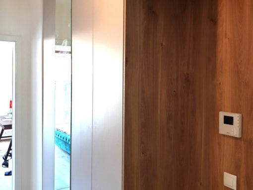 Realizace vestavěné skříňě do chodby s otevřenou dřevěnou částí a pantovými dveřmi.