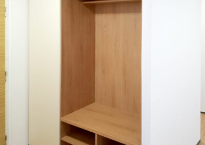 Realizace vestavěné skříně do chodby s botníkem, prostorem na věšáky a pantovými dveřmi.