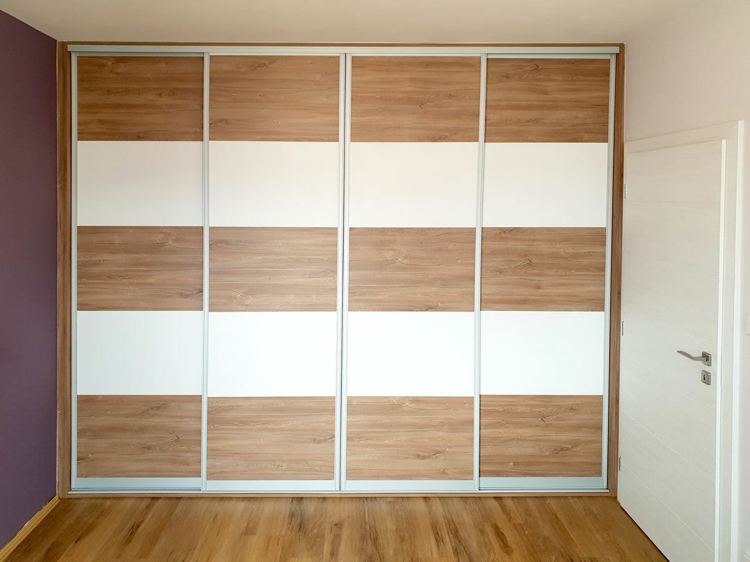 Realizace vestavěné skříně s posuvnými dveřmi do ložnice. Dveře jsou horizontálně dělené na pět částí.