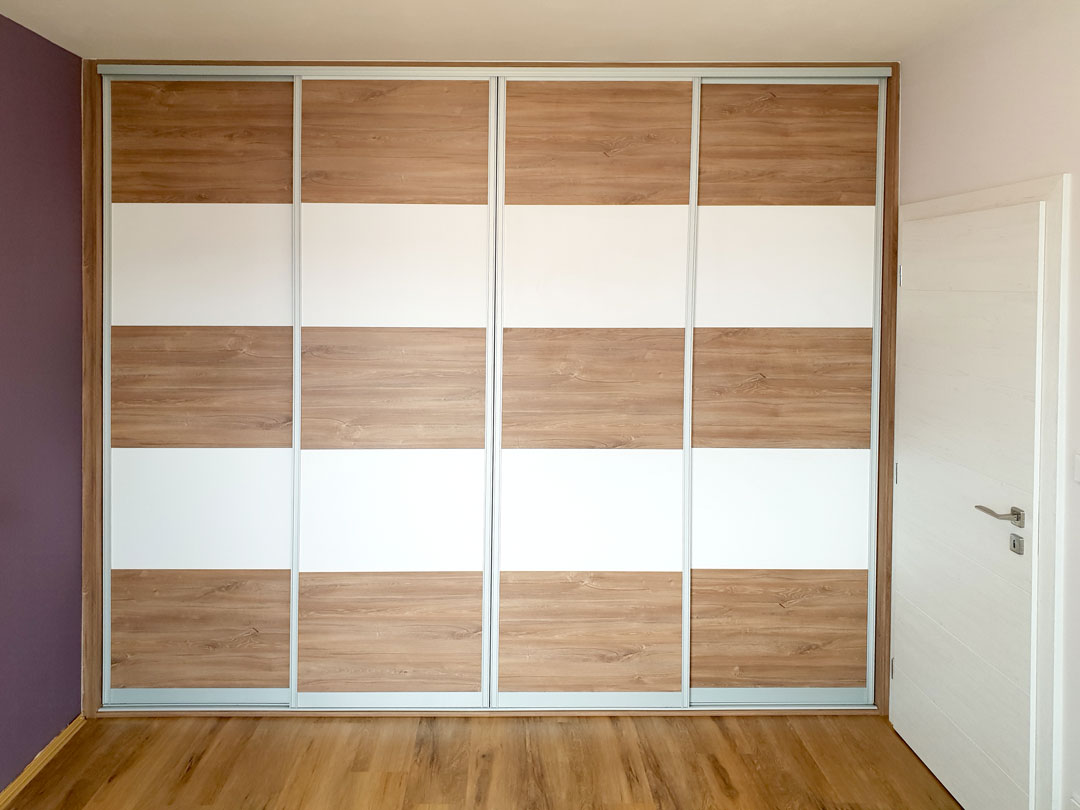 Realizace vestavěné skříně s posuvnými dveřmi do ložnice. Dveře jsou horizontálně dělené na pět částí.