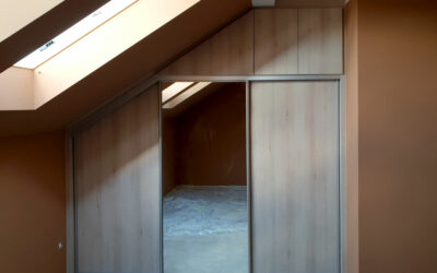 Skříň na míru do ložnice v podkroví v dekoru dřeva s kombinovanými posuvnými a pantovými dveřmi.