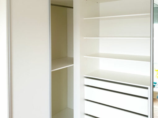 Interier rohové skříně na míru s posuvnými dveřmi v bílé barvě.