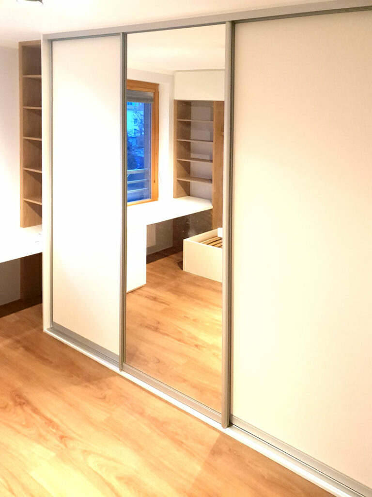 Realizace skříně na míru s posuvnými dveřmi a zakomponovaným pracovním stolem.