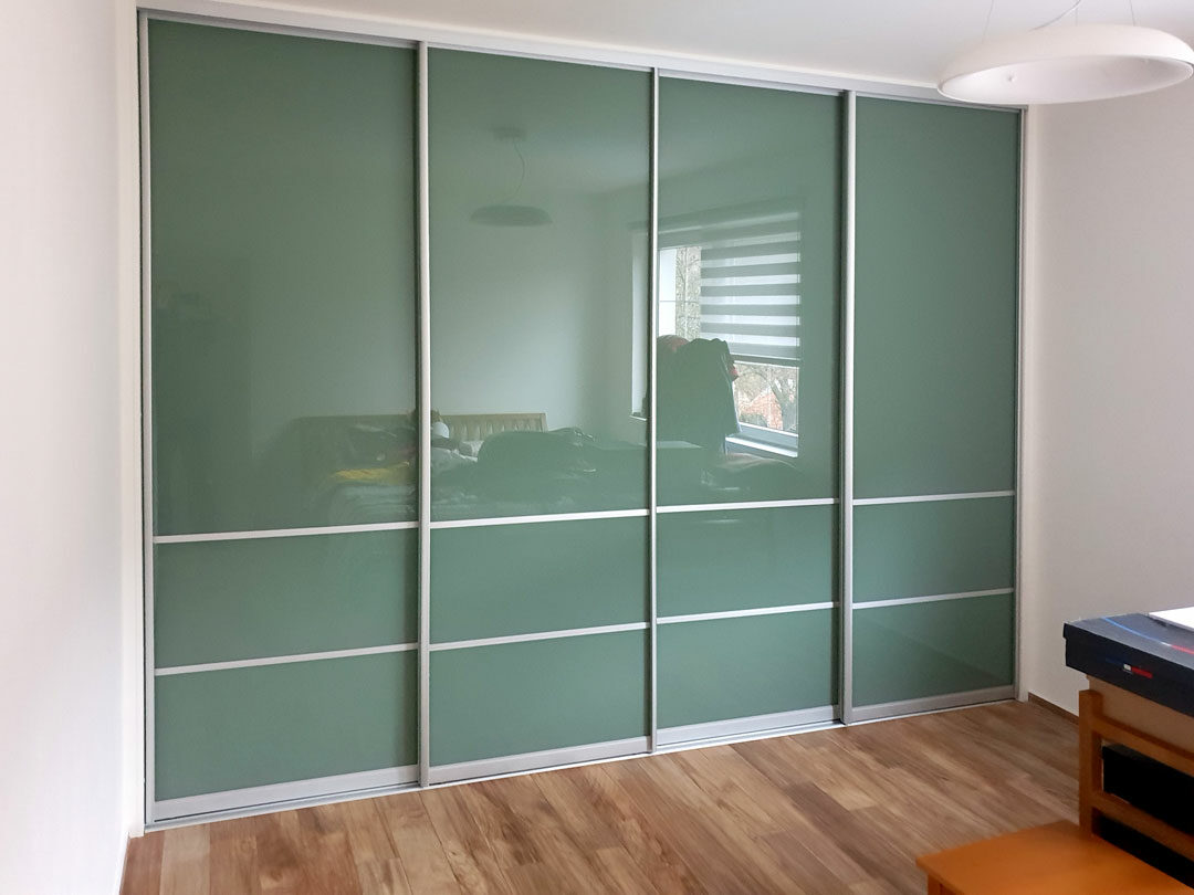 Realizace vestavěné skříně na míru s posuvnými dveřmi v hliníkovím rámu. Jako výplň byl použit zelený lacobel.