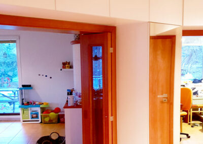 Vestavěné skříně na míru do chodby obestavující prostor kolem interierových dveří.
