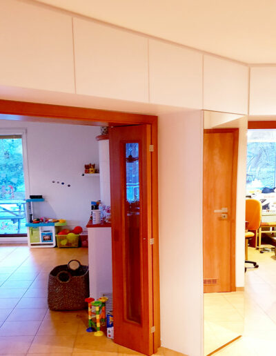 Vestavěné skříně na míru do chodby obestavující prostor kolem interierových dveří.