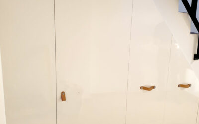 Realizace vestavěné skříně s pantovými dveřmi do prostoru pod schody v bílé barvě.