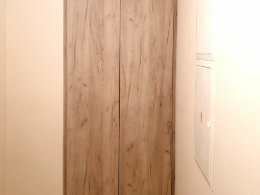 Vestavěná skříň do niky s pantovými dveřmi v dekoru přírodní dub.