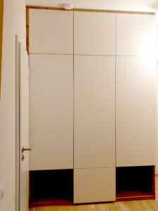 Vestavěná skříň s pantovými dveřmi v kombinaci bílých dveří a dřevěného korpusu.