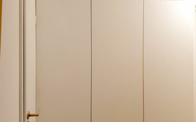 Vestavěná skříň s pantovými dveřmi v kombinaci bílých dveří a dřevěného korpusu.