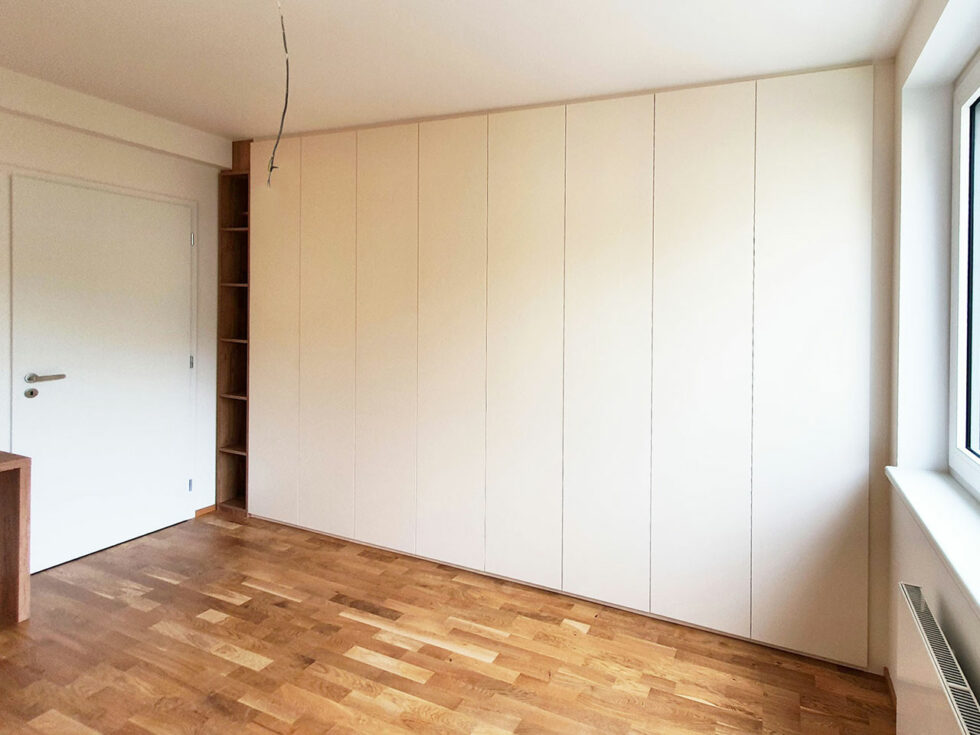 Vestavěná skříň s pantovými dveřmi, otevřenou poličkou a pracovním stolem.