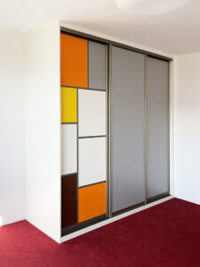 Vestavěná skříň s posuvnými dveřmi a dělením dveří do barevných segmentů.